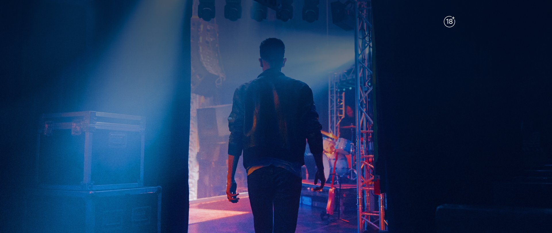 Event stage with vibrant lighting and a person standing in front of illuminated signage for a lifestyle rewards program.