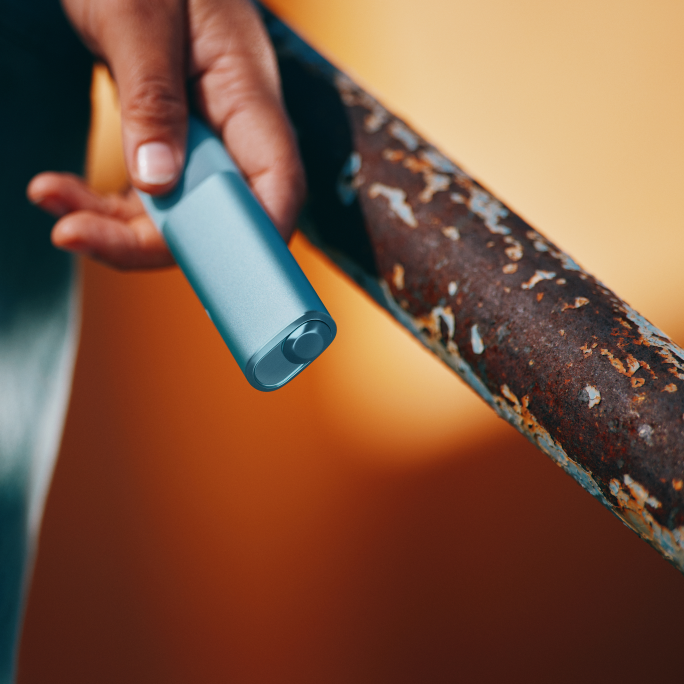 Persona levantando herramienta en azotea con IQOS Iluma i colgado en su overol