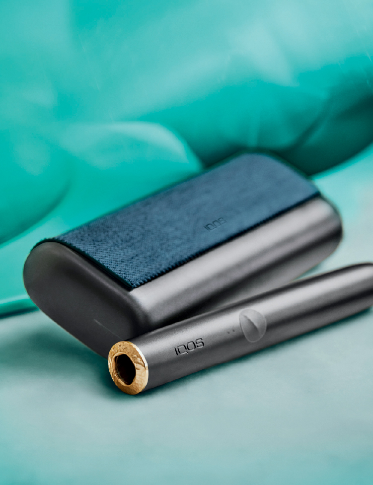 Turquoise IQOS Originals Duo device on a shiny coffee table.
