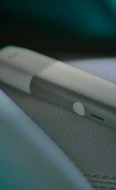 An IQOS ILUMA ONE device in a woman's hand.