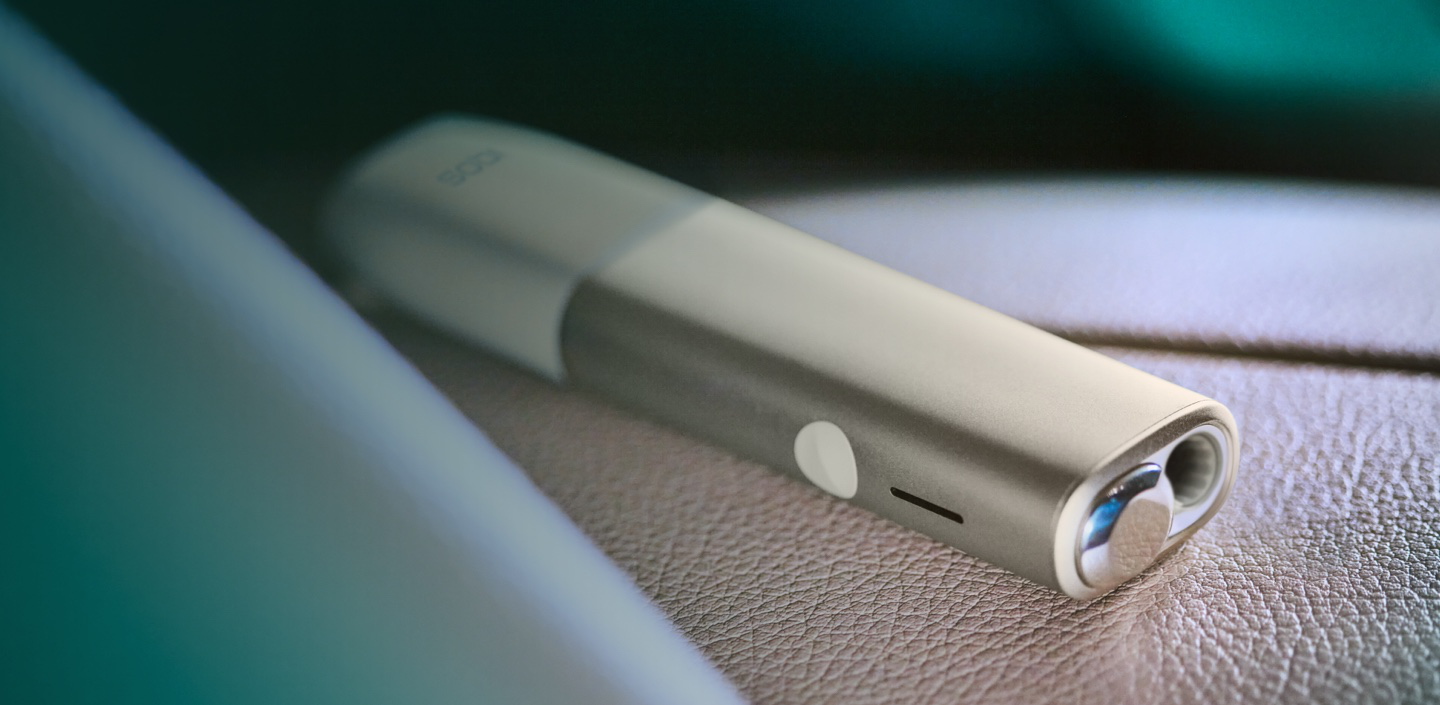 An IQOS ILUMA ONE device in a woman's hand.