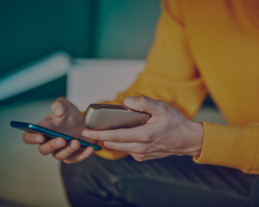 Young man with a mobile and IQOS 3 in his hands