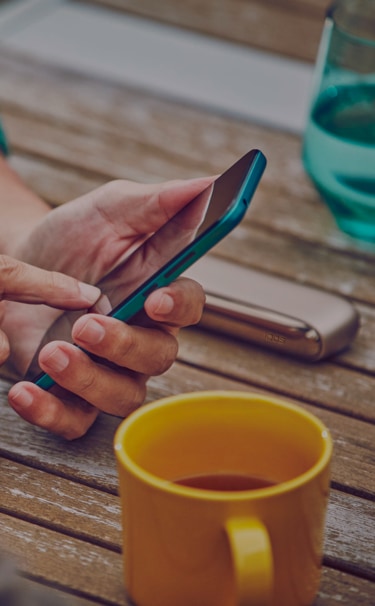 Man on a couch with his IQOS kit and the mobile in his hands Man on a couch with his IQOS kit and the mobile in his hands