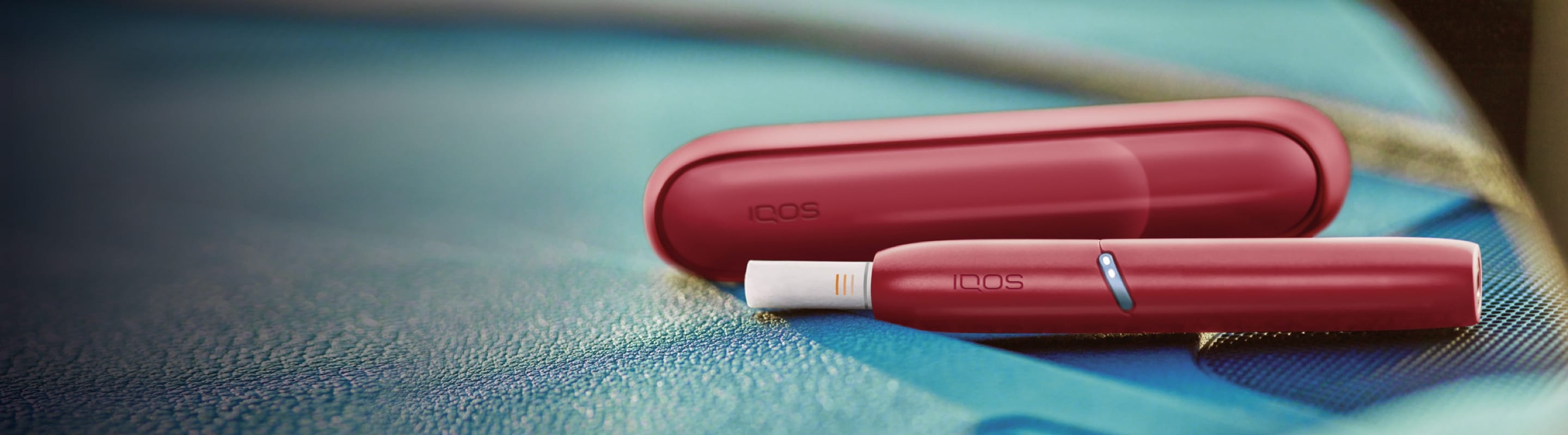 Two people sitting side by side; one holding an IQOS device.