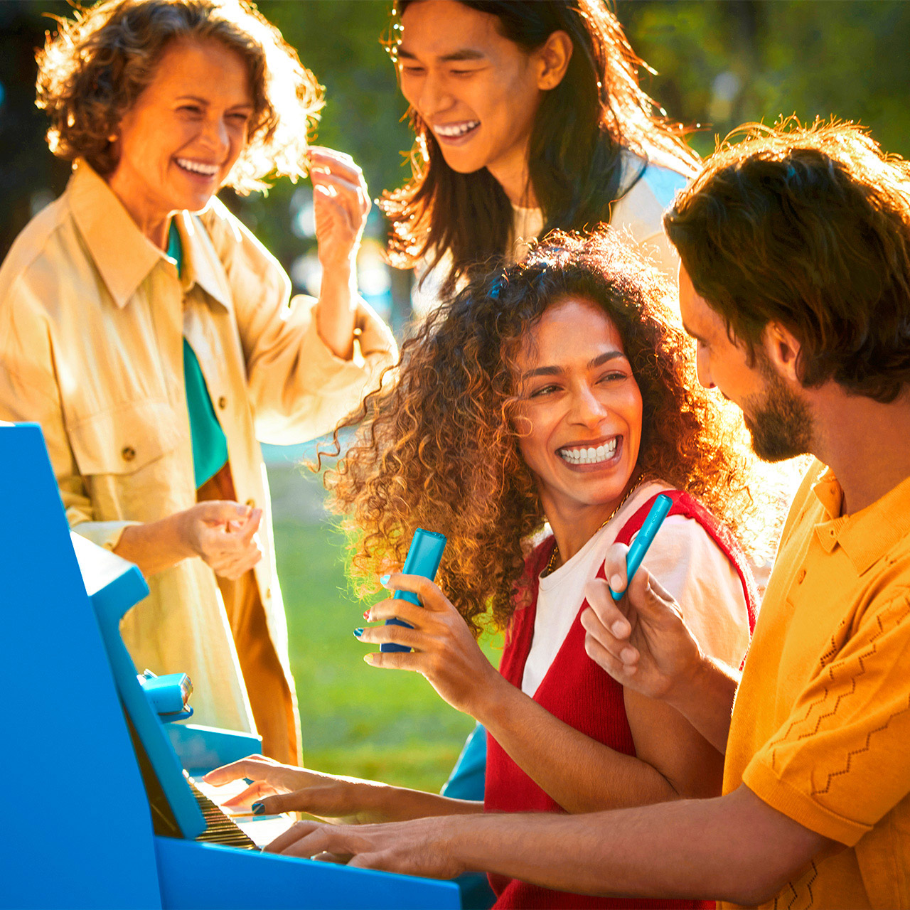 Čtyři lidé se usmívají a drží zařízení IQOS ILUMA WE z limitované edice.