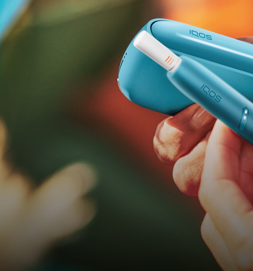 Hände halten ein IQOS Originals Duo in der Farbe türkis