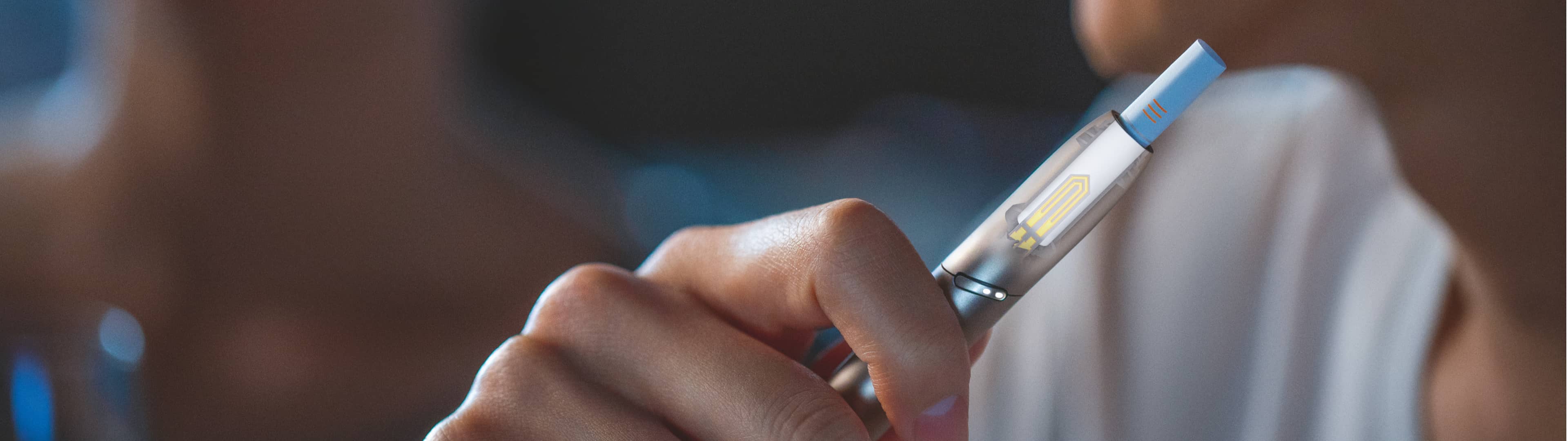 Hand hält silbernen IQOS DUO Holder, Heizblatt sichtbar