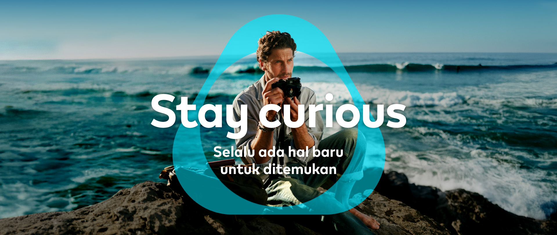 Banner Stay Curious IQOS – Seorang pria memegang kamera mencoba hal baru 