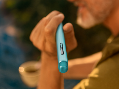 User holding breeze blue blue IQOS ILUMA i ONE device in hand.