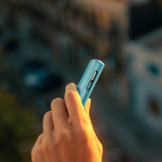 A hand is holding the IQOS ILUMA i One Breeze Blue tobacco heating device.