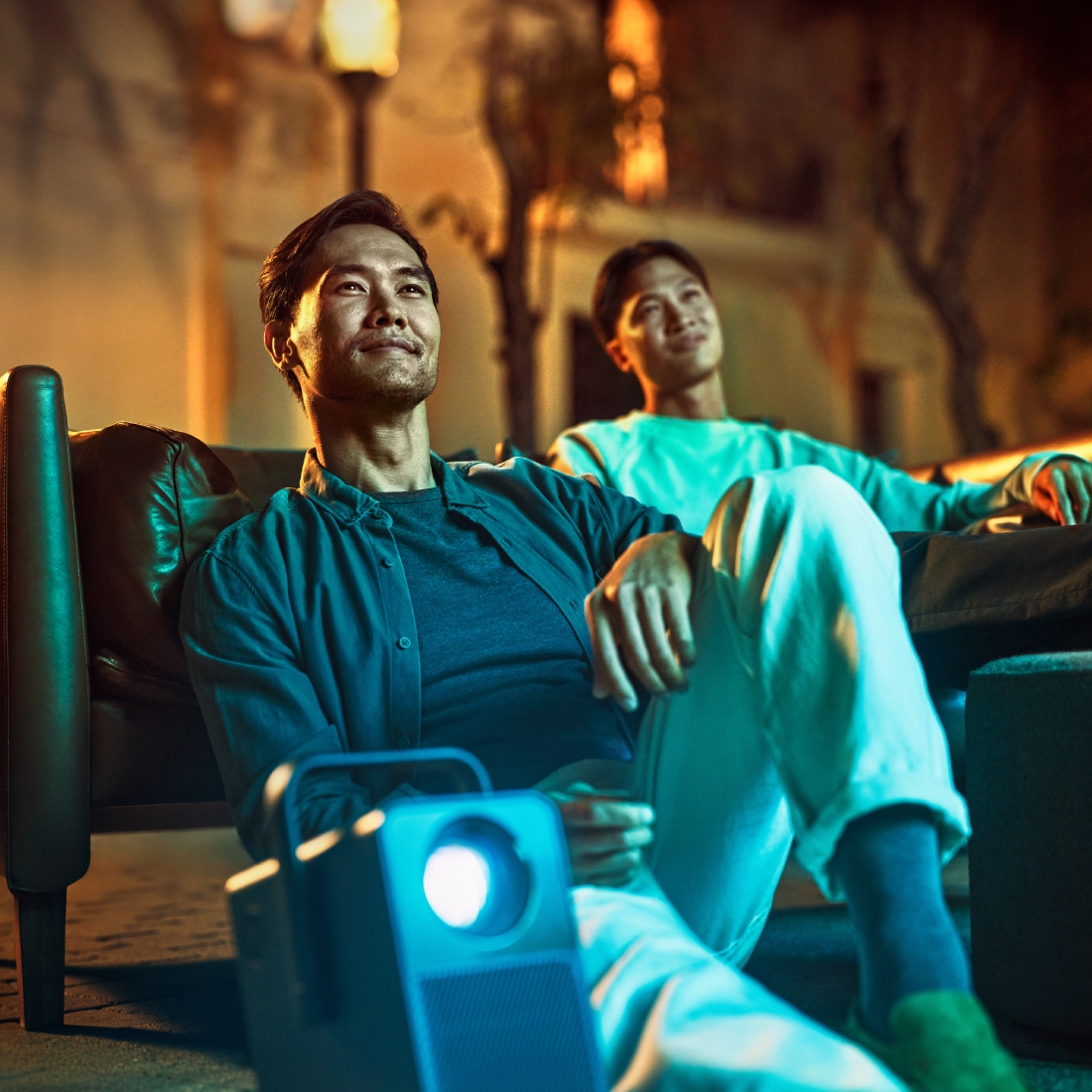 Двое мужчин сидят на диване, рядом проектор