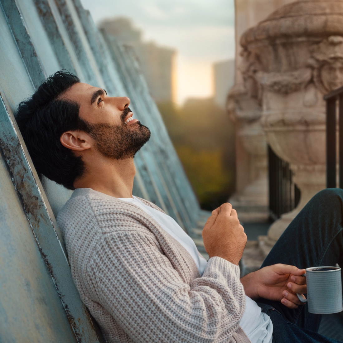 Мужчина сидит на крыше с кофе и смотрит в небо