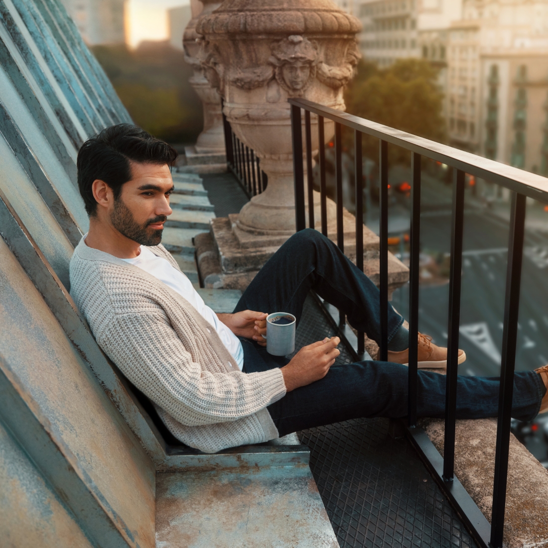 Мужчина сидит на крыше с кофе