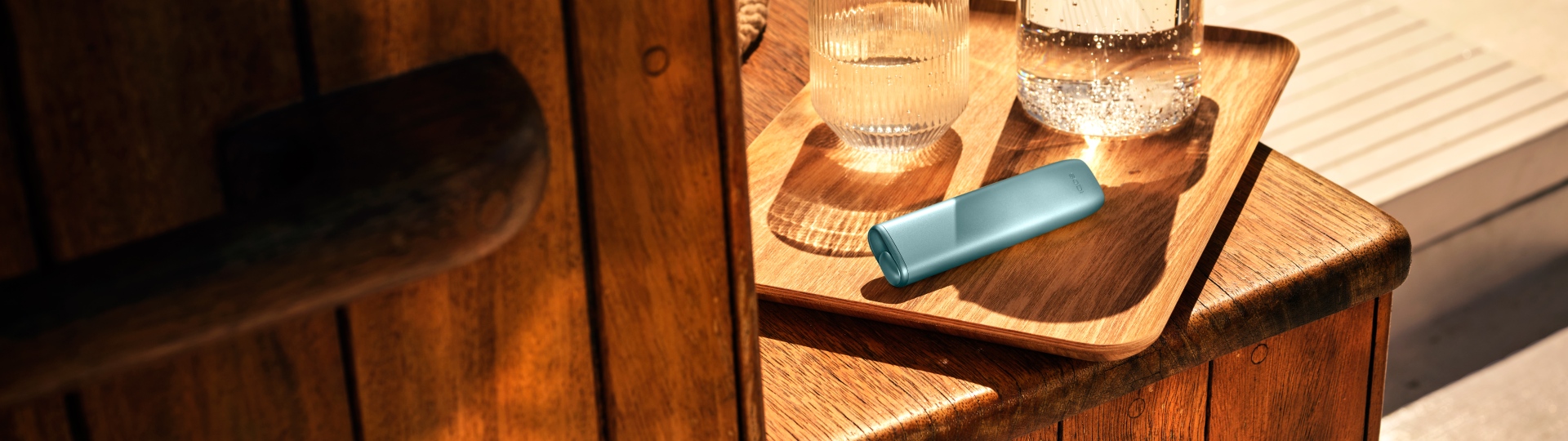 Устройство IQOS ILUMA i ONE цвета Лазурный бриз на деревянной доске