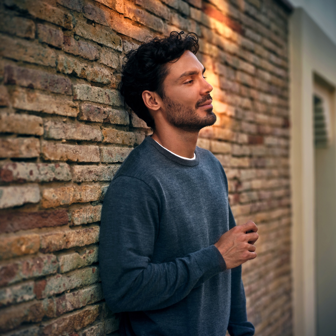 Мужчина стоит около кирпичной стены