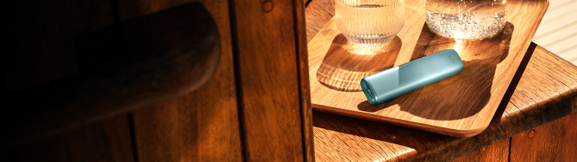 Устройство IQOS ILUMA i ONE цвета Лазурный бриз на деревянной доске