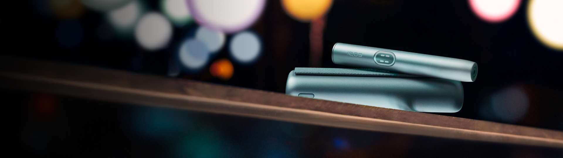 Устройство IQOS ILUMA i PRIME цвета Лазурный бриз на перилах