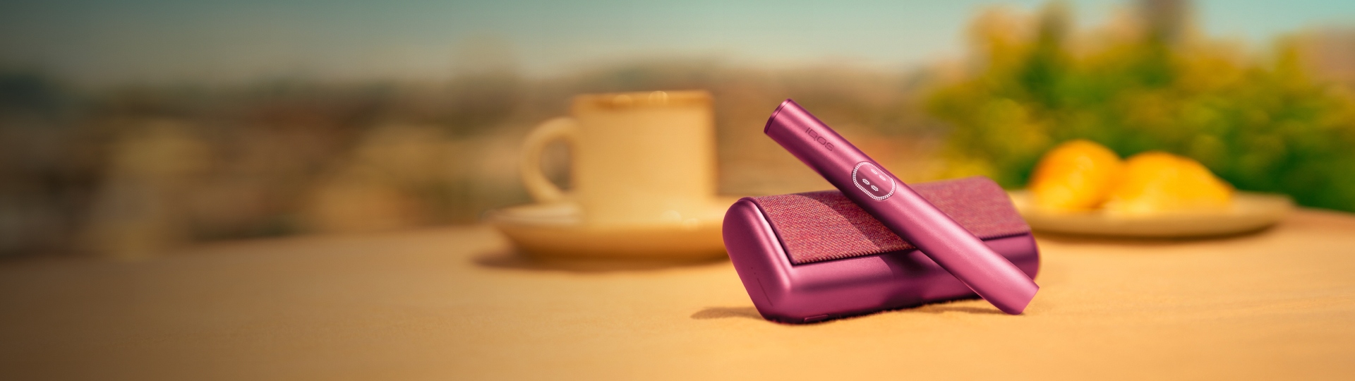 Garnet Red IQOS ILUMA i PRIME device above its charger