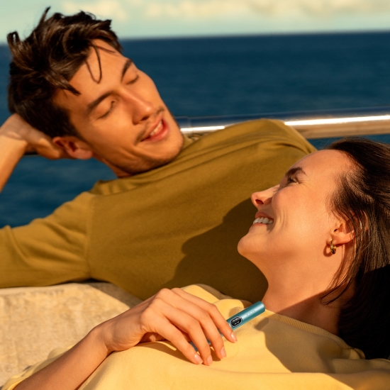 A man and a woman looking at each other, while holding an IQOS ILUMA i PRIME device