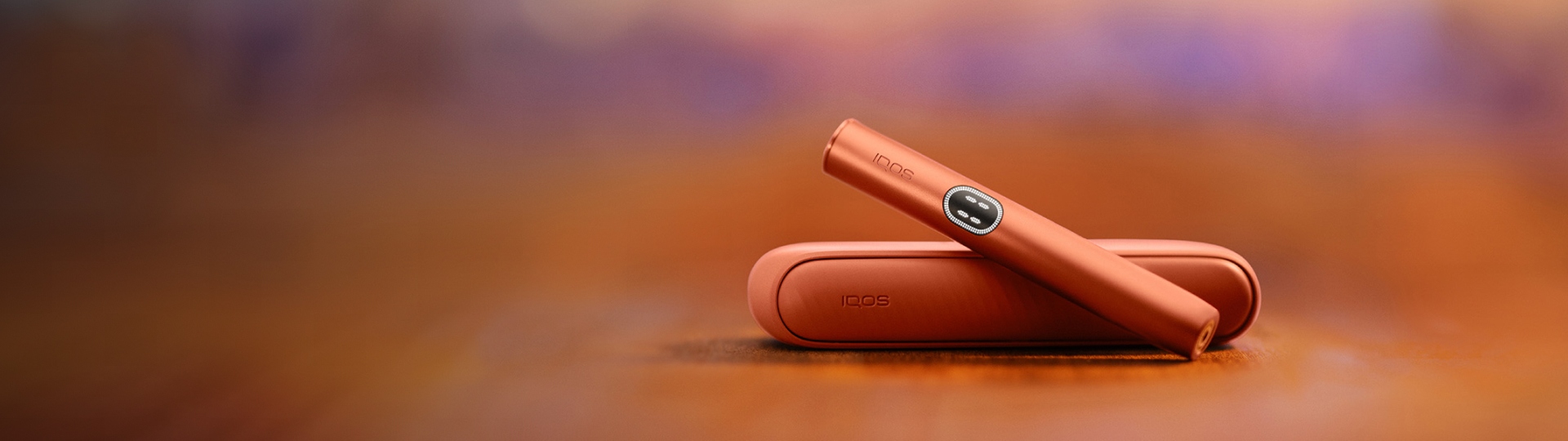 Terracotta IQOS ILUMA i device above its charger, with red background