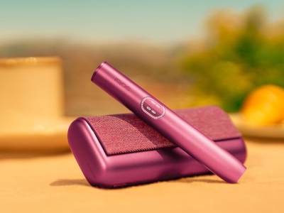 Garnet Red IQOS ILUMA i PRIME device above its charger