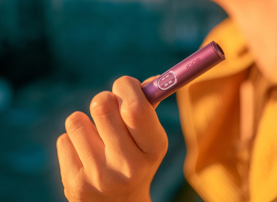 Hand holding an IQOS ILUMA i Holder Garnet Red