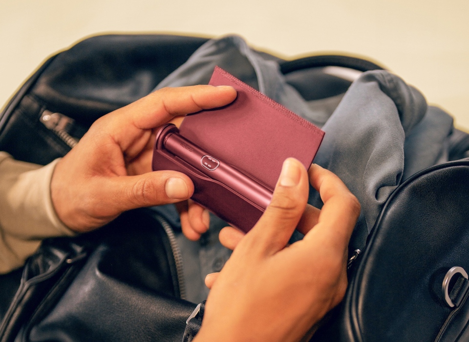 Hand flipping the leather door for IQOS ILUMA i PRIME Charger Garnet Red to reveal its Holder