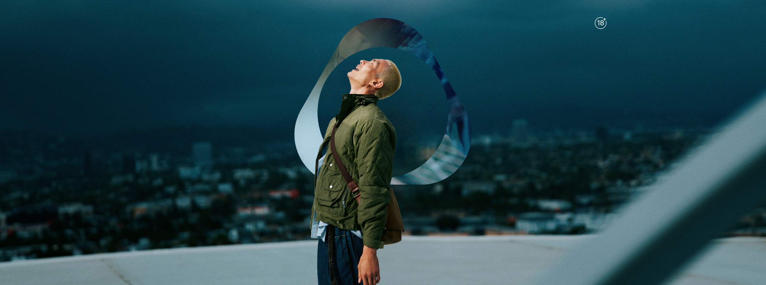 Adult person in green jacket outdoors with IQOS key visual abstract loop design and cloudy blue sky background.