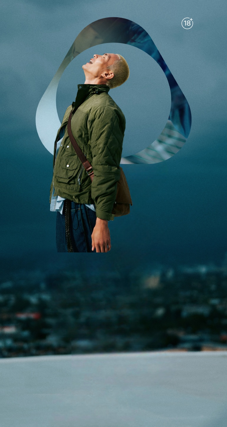 Adult person in green jacket outdoors with IQOS key visual abstract loop design and cloudy blue sky background.