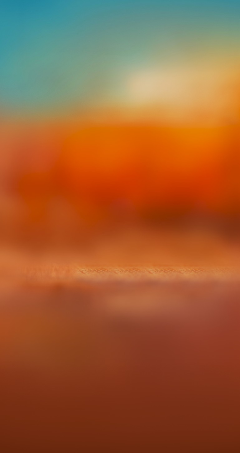 Close-up of an IQOS ILUMA i PRIME with a TEREA stick inserted on its holder. The holder is resting on top of its pocket charger, set against a warm orange-red gradient background.