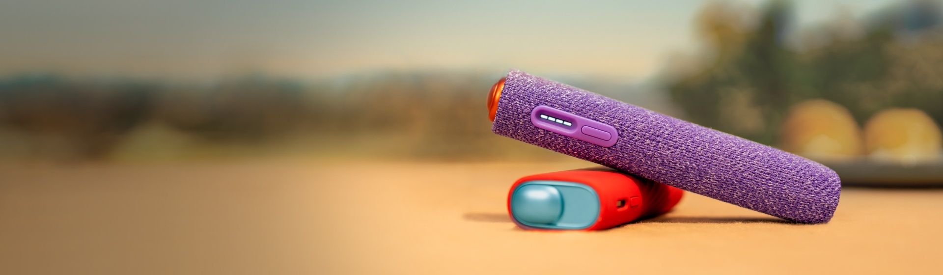 Soft outdoor background with IQOS ILUMA i ONE wrapped in a protector sleeve on the foreground.