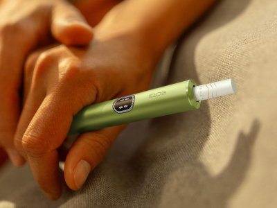 Two hands holding an IQOS ILUMA i device