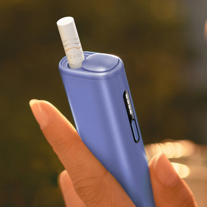 Hand holding a violet IQOS ILUMA i ONE device