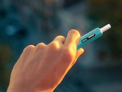 Hand holding a blue IQOS ILUMA i ONE device