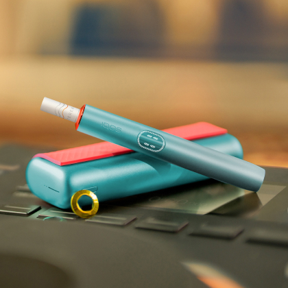 Blue IQOS ILUMA i PRIME device above its charger, customized with wrap and rings
