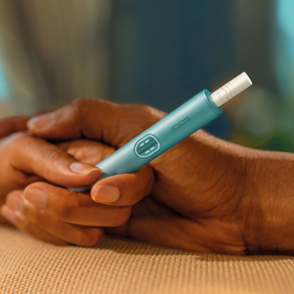 Two hands holding together an IQOS ILUMA i PRIME device