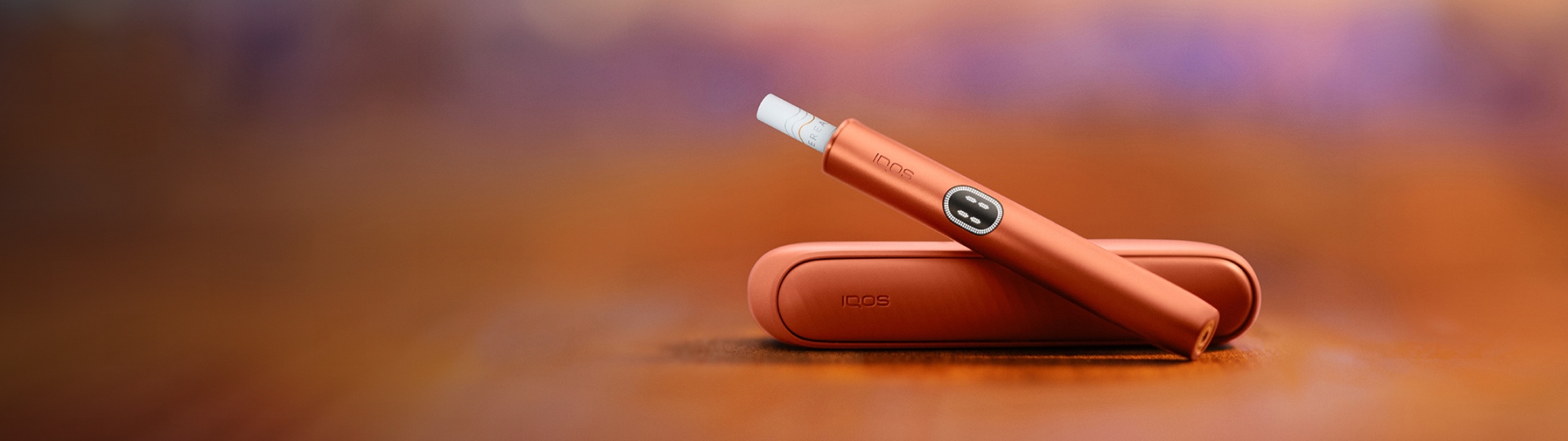 Terracotta IQOS ILUMA i device above its charger, with red background