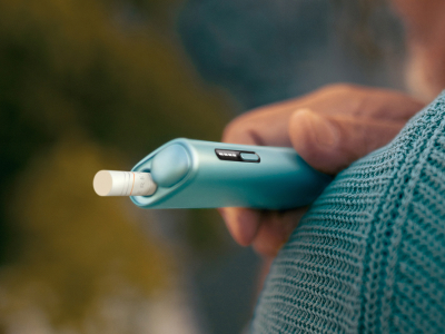 Hand holding an IQOS ILUMA i ONE device