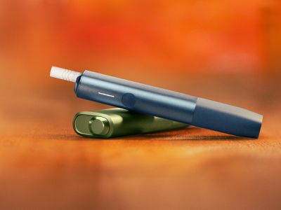 Blue IQOS ILUMA i ONE above a green IQOS ILUMA i ONE, with red background