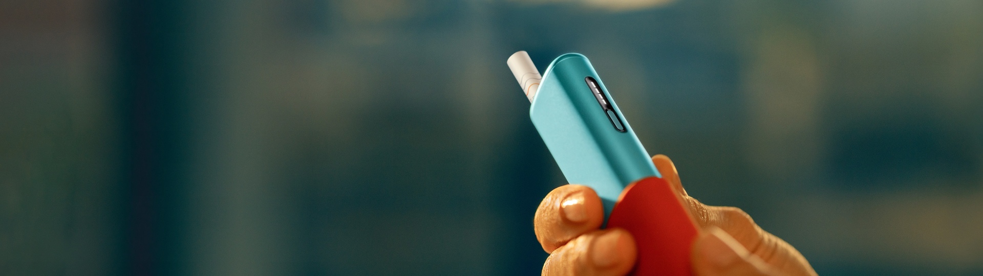 Hand holding an IQOS ILUMA i ONE device, taking it out of its sleeve