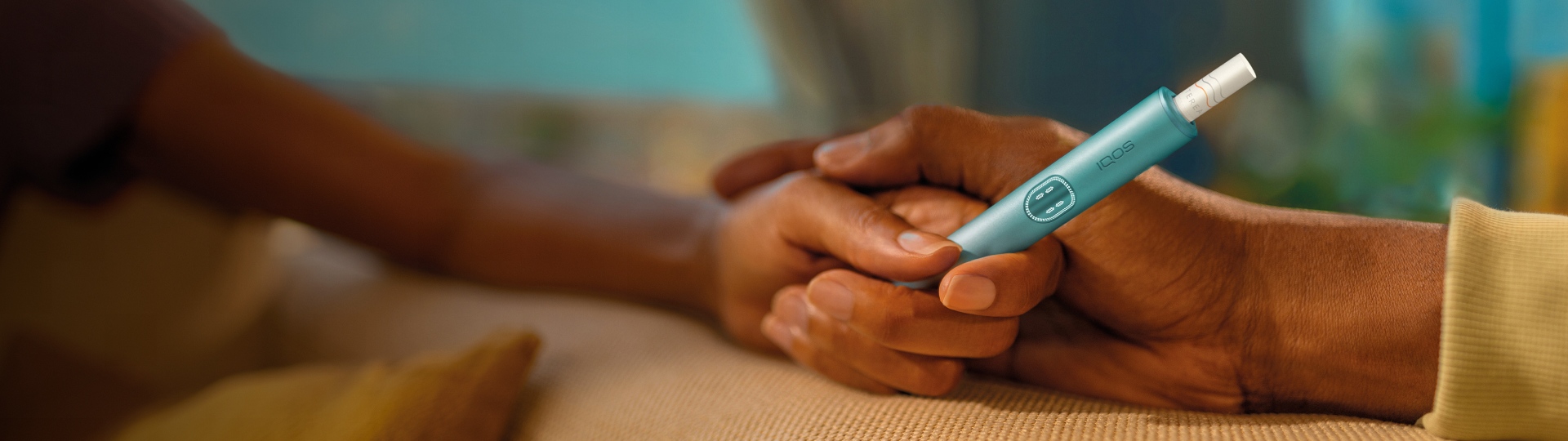 Two hands holding together an IQOS ILUMA i PRIME device