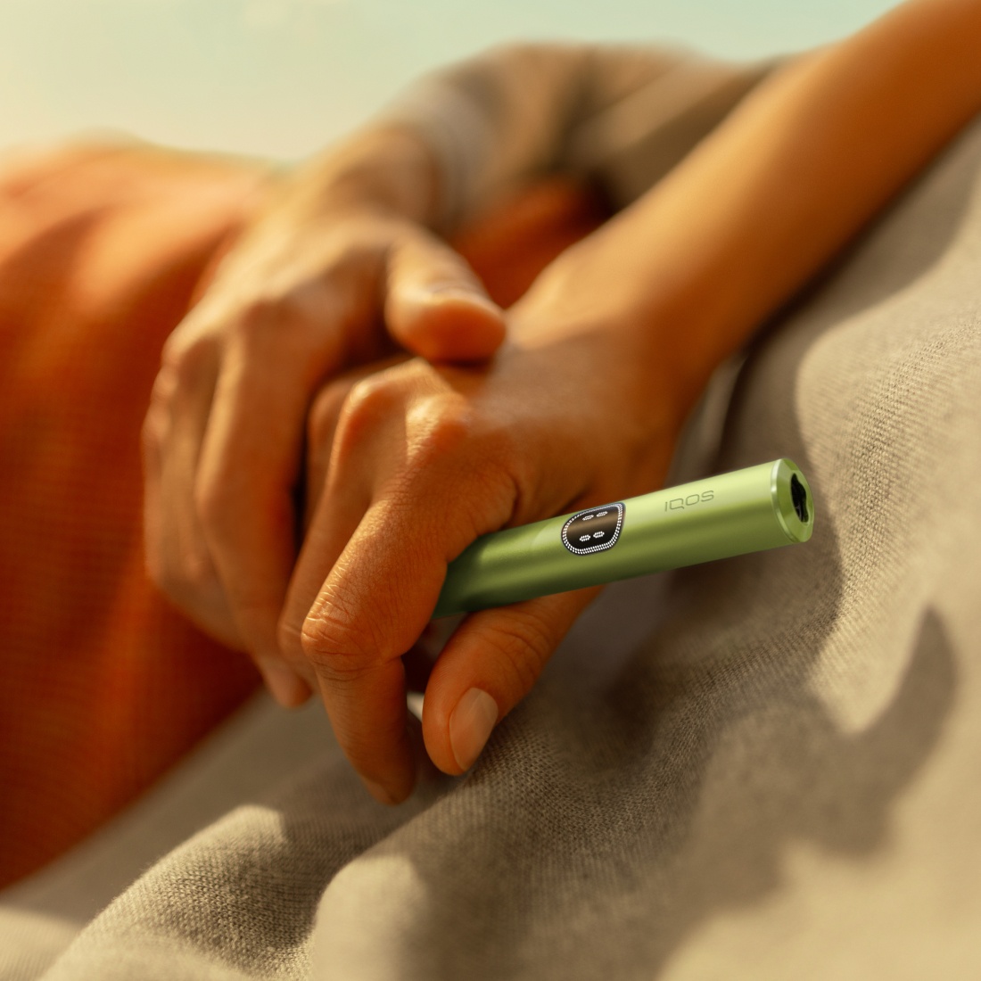 Hand hält einen IQOS ILUMA i Holder in Leaf Green.