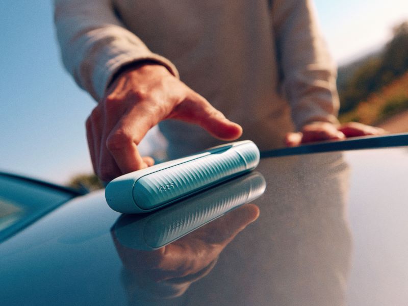 Eine Hand reicht nach einem IQOS ILUMA i in Breeze Blue