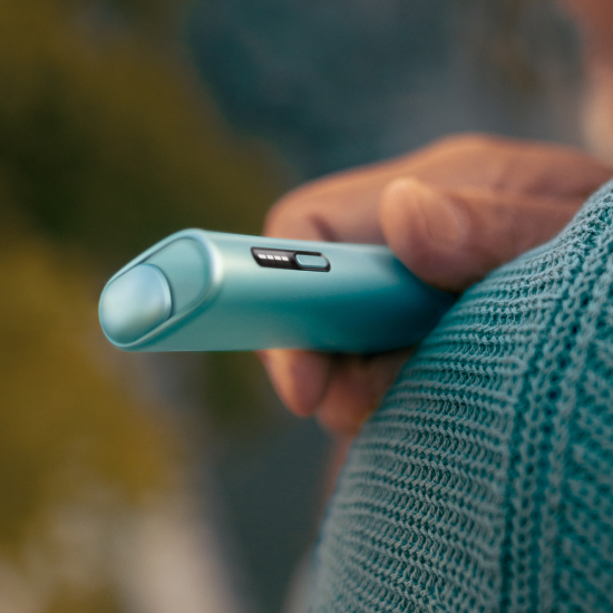 Hand hält einen IQOS ILUMA i ONE in Breeze Blue.