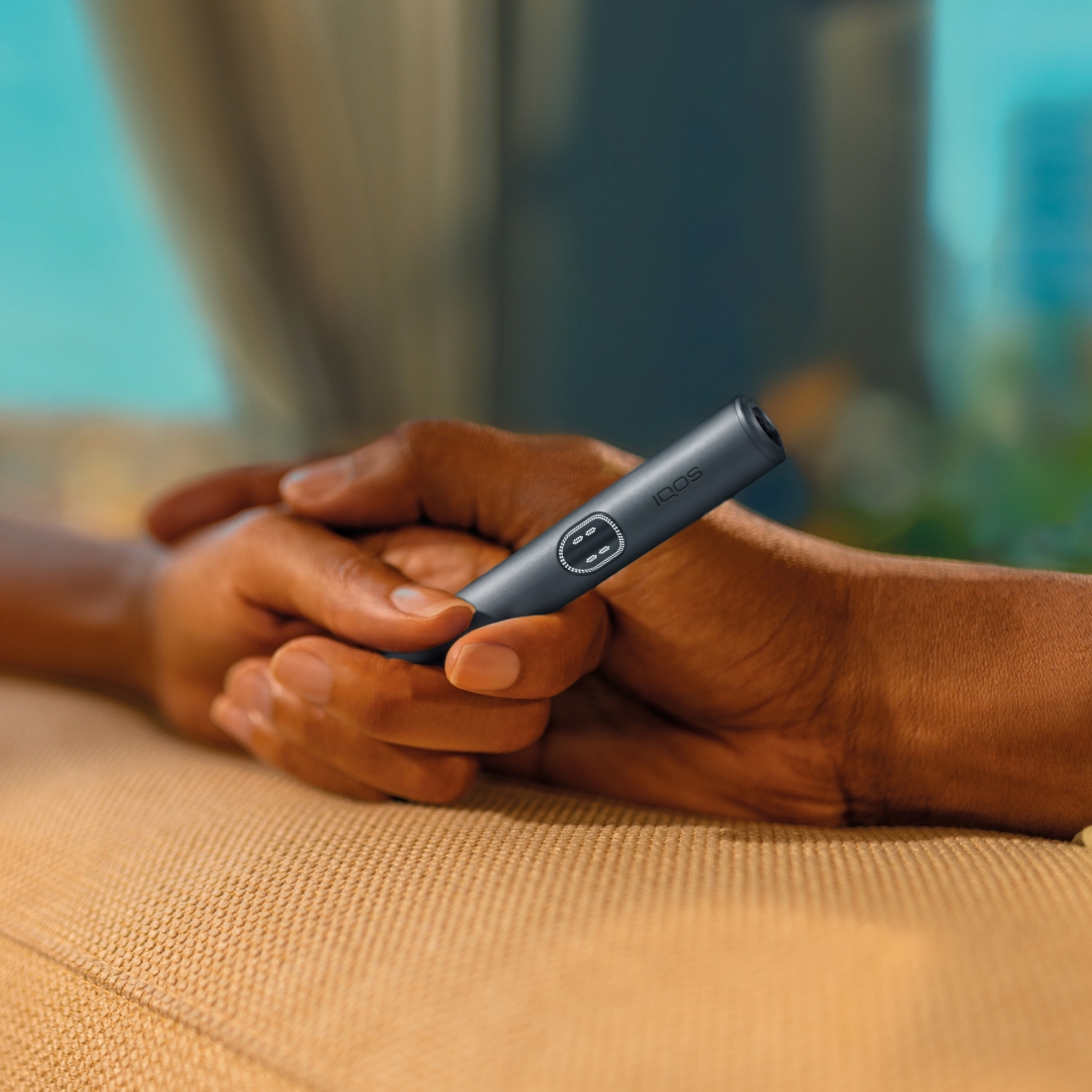 Zwei Hände halten einen IQOS ILUMA i PRIME Holder in Midnight Black.