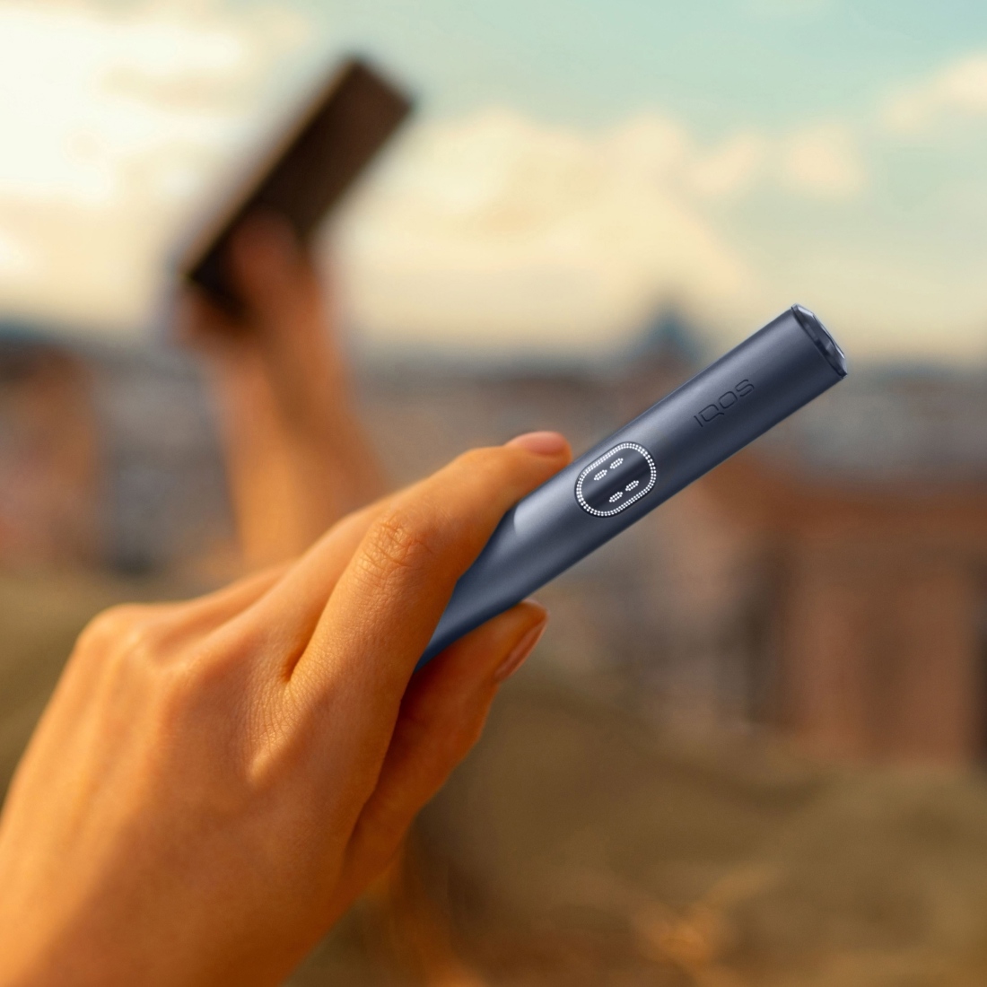 Hand hält einen IQOS ILUMA i PRIME Holder in Midnight Black.
