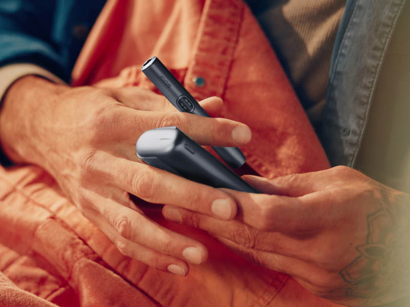 Eine Hand hält ein IQOS ILUMA i PRIME Gerät in der Farbe Midnight Black in zwei Händen