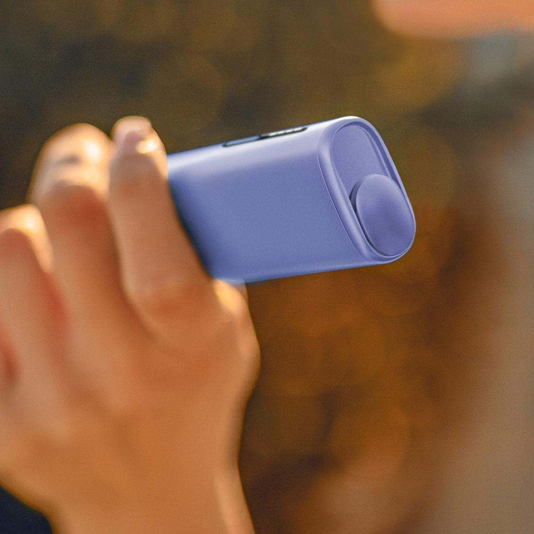 Eine Hand hält ein IQOS ILUMA i ONE Gerät in der Farbe Digital Violet.