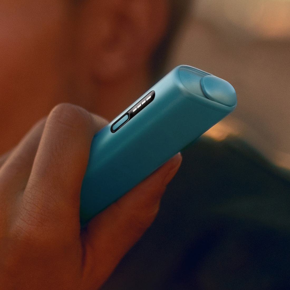 Eine Hand hält ein IQOS ILUMA i ONE Gerät in der Farbe Breeze Blue.