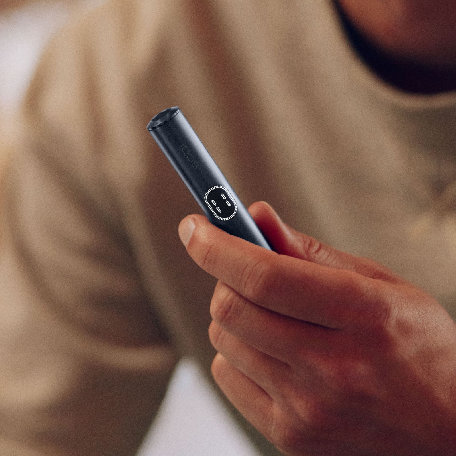 Hand hält ein IQOS ILUMA i Gerät mit Touchscreen